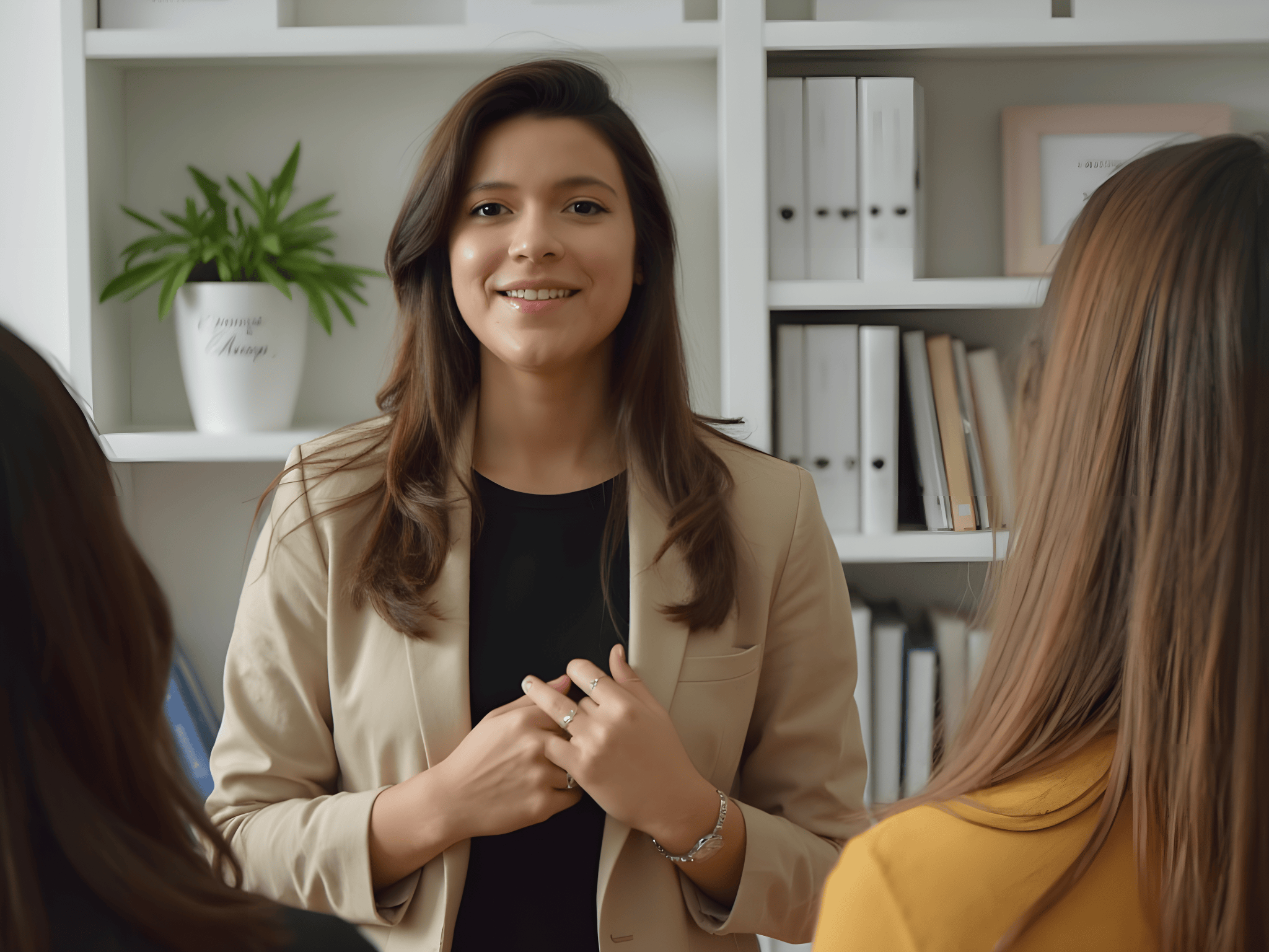 Professional woman speaking to a group in a modern office setting, showcasing leadership and communication skills.