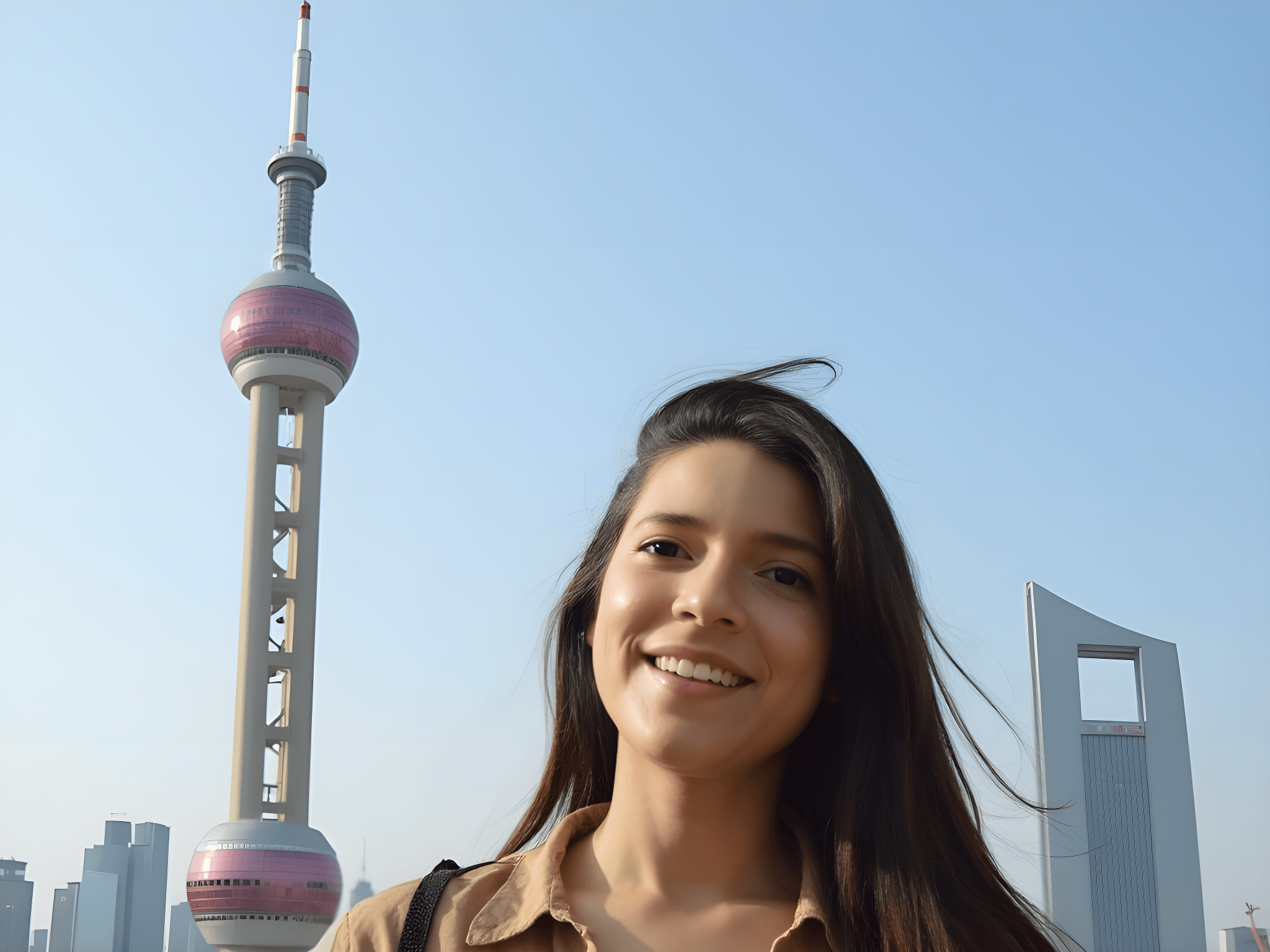 Smiling woman with long hair in front of the Oriental Pearl Tower in Shanghai, blue sky background.