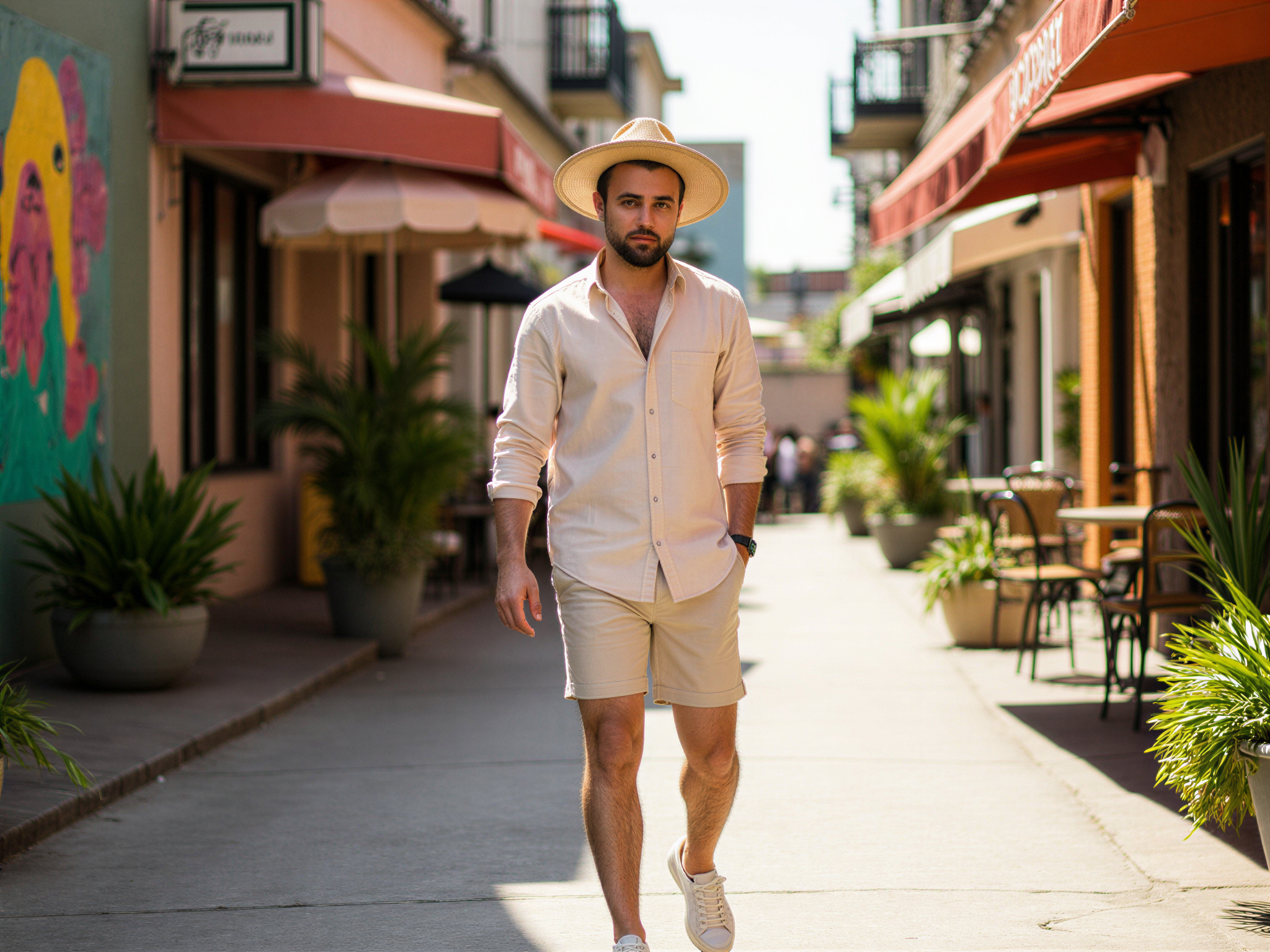 A 32-year-old male, OD62S, exuding a joyful spirit as he strolls through vibrant urban laneways, showcasing a relaxed yet stylish vibe. Dressed in a light linen shirt and tailored shorts, he pairs his look with sleek sneakers and a playful straw hat. The colourful street art and bustling cafés provide a lively backdrop, creating a cheerful ambiance. Sunlight filters through the buildings, casting warm, inviting shadows. His expression is bright, with a genuine smile that captures the essence of a carefree summer day amidst the cityscape.