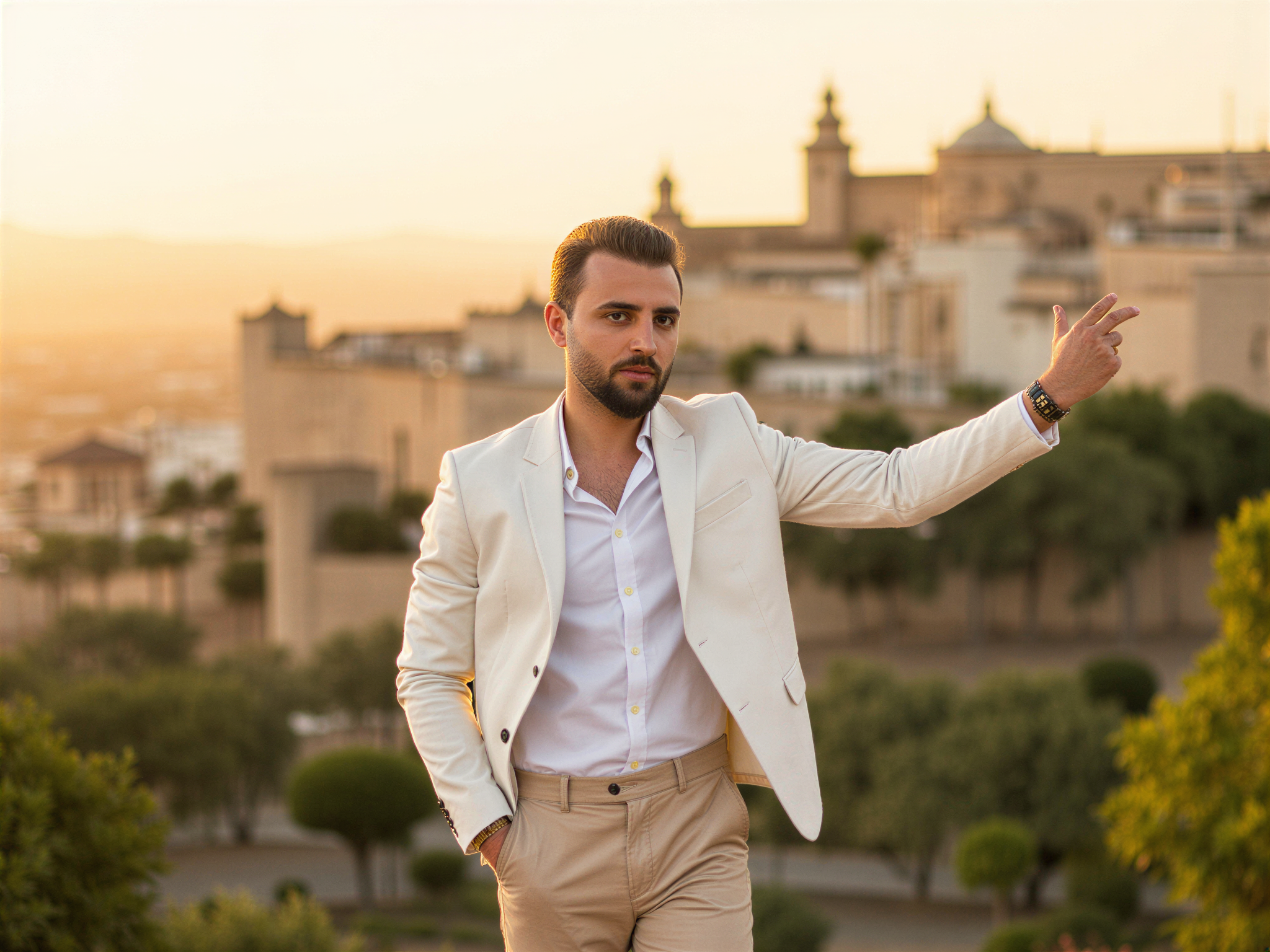 A vibrant and spirited male figure, OD62S, aged 32, capturing the essence of Granada's stunning landscapes. He stands against the picturesque backdrop of Alhambra, dressed in a lightweight, linen white shirt and tailored light beige trousers, embodying a relaxed yet stylish summer vibe. With a wide, genuine smile, he exudes happiness and warmth, as he gestures toward the breathtaking view. The setting sun bathes the scene in a golden glow, highlighting his features and the intricacies of his attire. The idyllic atmosphere conveys a sense of joy and appreciation for the beauty surrounding him, creating an enchanting snapshot of life in Granada.