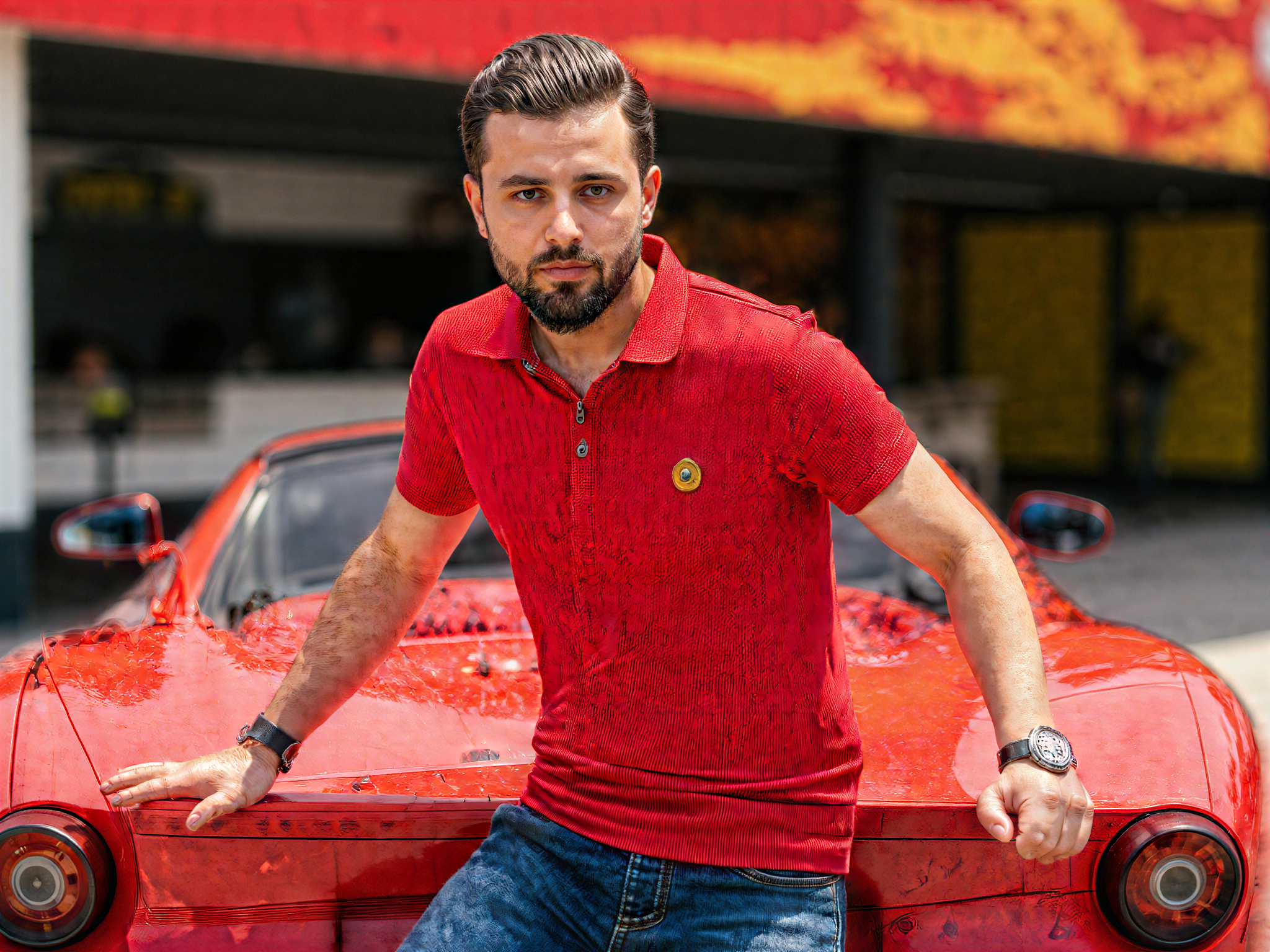 A joyful male figure, OD62S, aged 32, is standing in front of an iconic Ferrari at Ferrari World, embodying the thrill of speed and luxury. He is casually dressed in a vibrant red polo shirt and well-fitted jeans, exuding an energetic and exuberant demeanor. The background showcases the vibrant architecture of Ferrari World, with its sleek lines and bold colors reflecting the automobile’s aesthetic. The sunlight casts playful shadows, enhancing the mood of happiness and excitement. His wide smile captures the joy of being in a dream-like automotive paradise, as he poses with an arm thrown casually over the car's hood, embodying both charisma and enthusiasm for adventure.