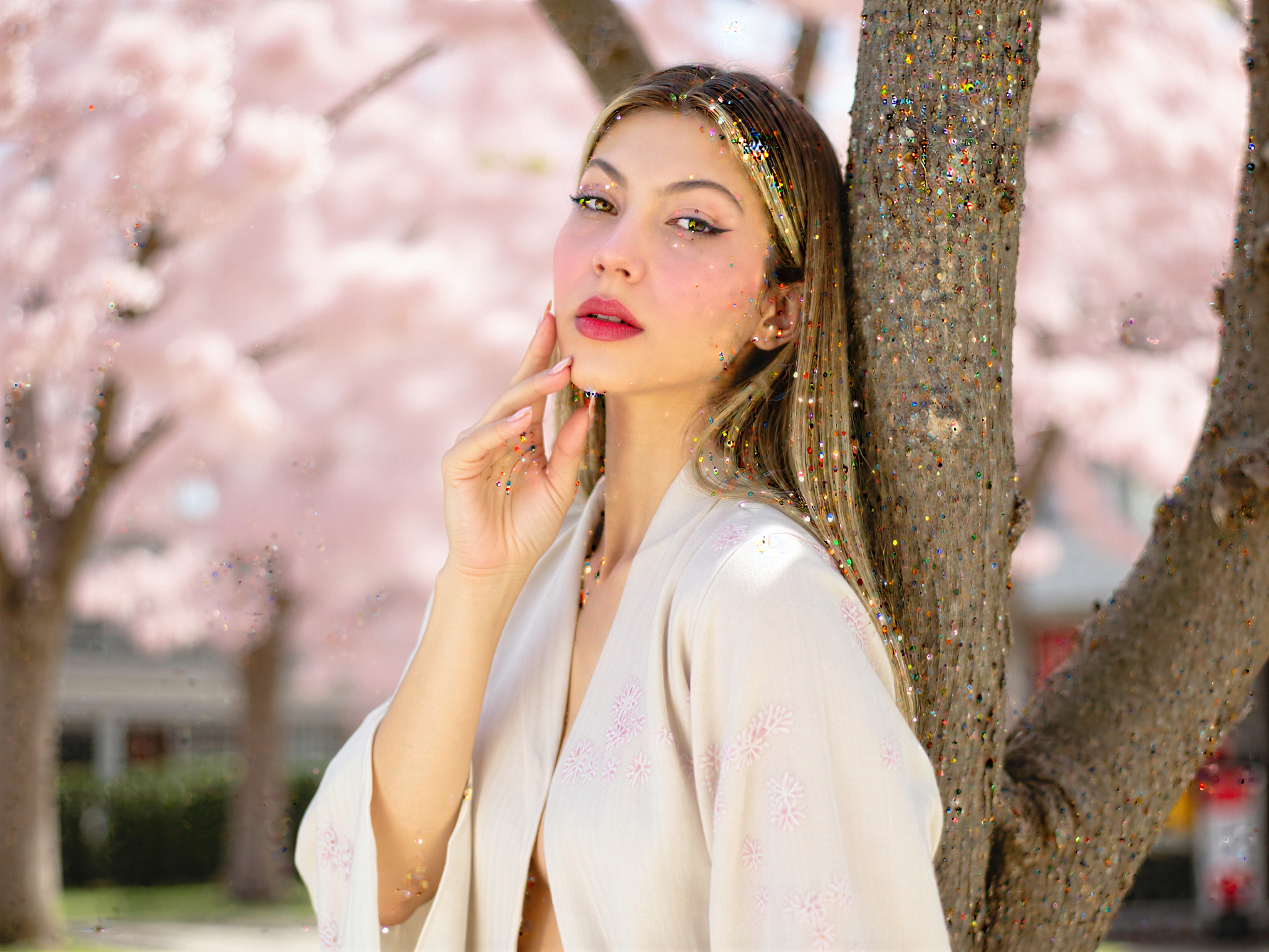 A joyful female individual, OD62S, aged 28, captured in a picturesque Kyoto setting during cherry blossom season. She wears a flowing, pastel-colored kimono adorned with delicate floral patterns, gracefully complementing the soft pink petals surrounding her. Sunlight filters through the branches, creating a dreamy, dappled effect on her face. Her expression radiates happiness, with her eyes sparkling and a gentle smile as she leans against a cherry blossom tree, surrounded by the vibrant culture of Kyoto. The image embodies a serene yet joyful atmosphere, perfect for an editorial in a high-fashion magazine.