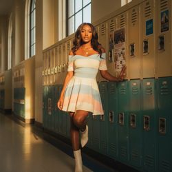 Emily, a 25-year-old black woman, stands confidently in a sun-drenched corridor of a retro high school building. She wears a stylish off-the-shoulder varsity-inspired dress made of soft cotton, adorned with pastel-hued stripes that evoke classic collegiate colors. The dress cinches at the waist, flowing into a playful A-line silhouette that sways with her movements. Her long hair cascades in effortless waves, and she accessorizes with a delicate gold chain with a tiny heart pendant. Paired with ivory leather ankle boots, she leans casually against lockers with one knee bent, exuding an air of confidence. The golden hour sunlight filters through the windows, casting a warm glow, enhancing the soft textures of her outfit amidst vintage lockers and school spirit posters, encapsulating a nostalgic yet glamorous moment.