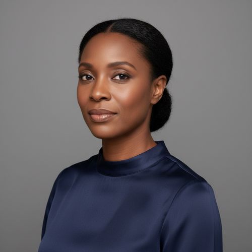 Female portrait with dark hair in a sleek bun, wearing a navy blouse, showcasing a confident expression against a neutral background.