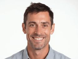 Smiling man in a light blue shirt against a white background.