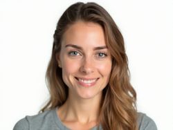 Smiling young woman with long hair in a gray shirt against a light background.